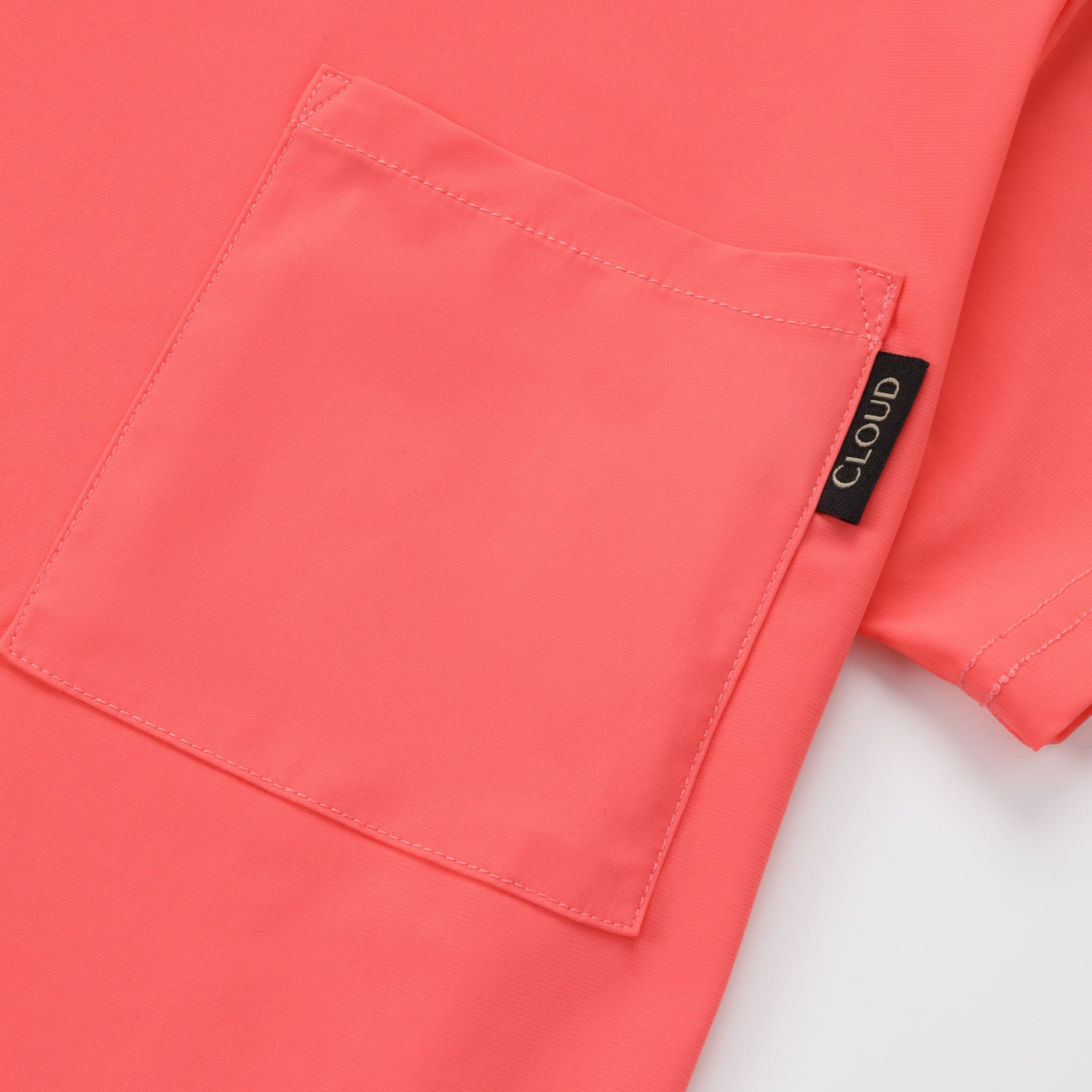 Close-up of a coral-colored shirt with a brand label on a white background
